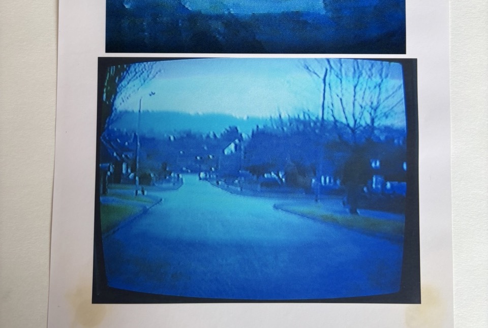 Photograph of video monitor showing still image of road junction and a tree lined horizon